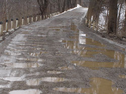 Image of a gravel road with many potholes 