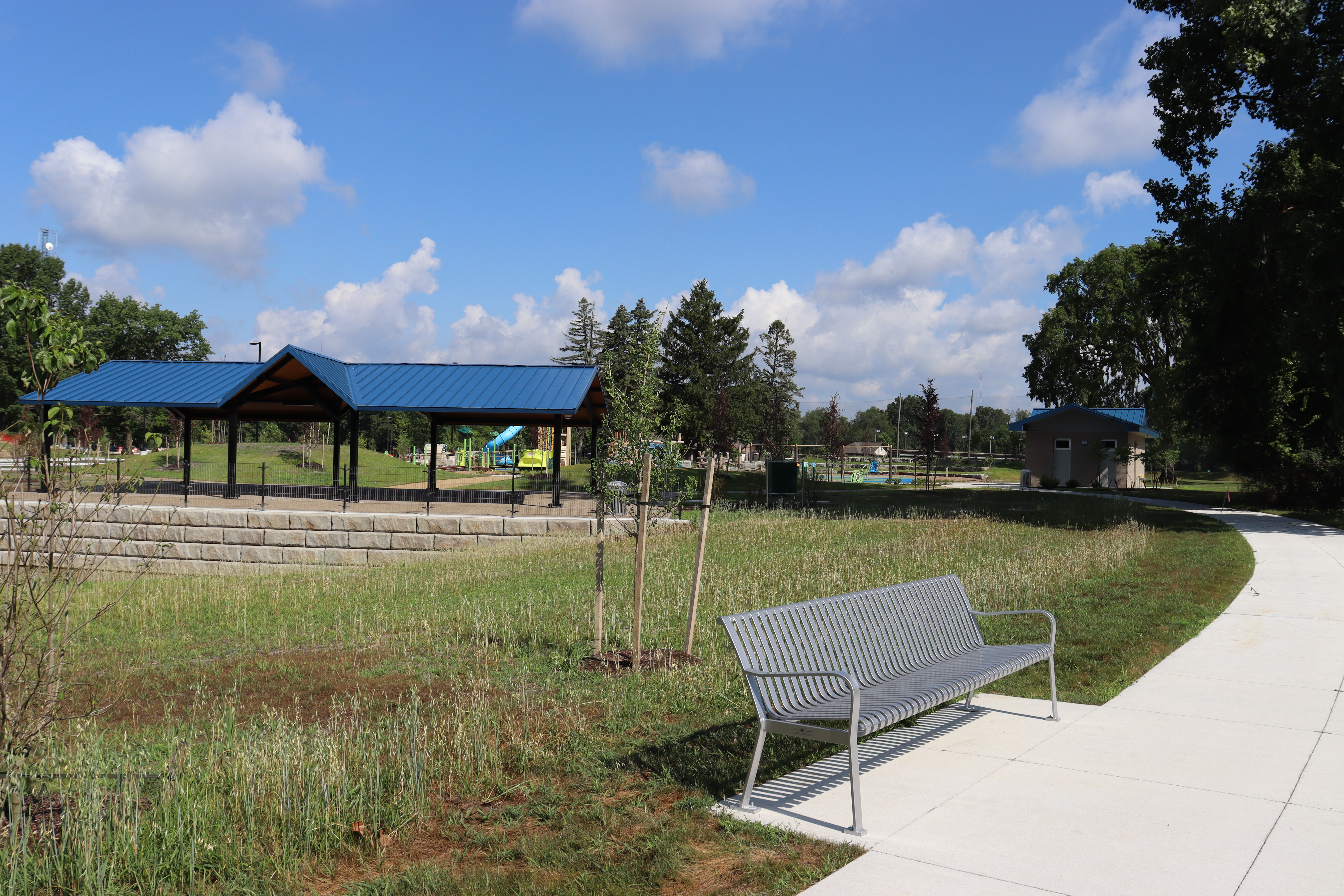 Beech Woods Park Shelter #2, $400 per day, capacity 150 guests with 18 picnic tables. Photos show a modern blue-roof shelter located next to the new playground.