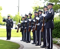 A line of soldiers stand listening to an officer